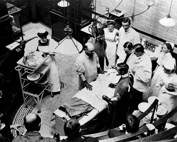 Leikkaus alkamassa Charing Crossin sairaalassa (1818–) Lontoossa 1900; hoitajista kahdella pitää kiirettä. (Kuva Wikimedia Commons)